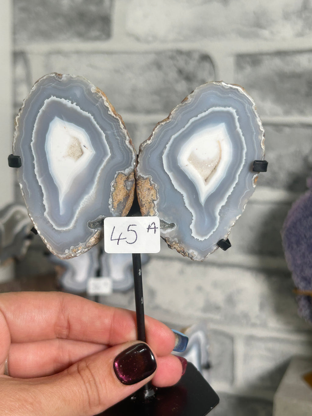 Blue banded agate nodule pair from Indonesia on a custom black metal stand, showing symmetrical blue-grey and white chalcedony banding.